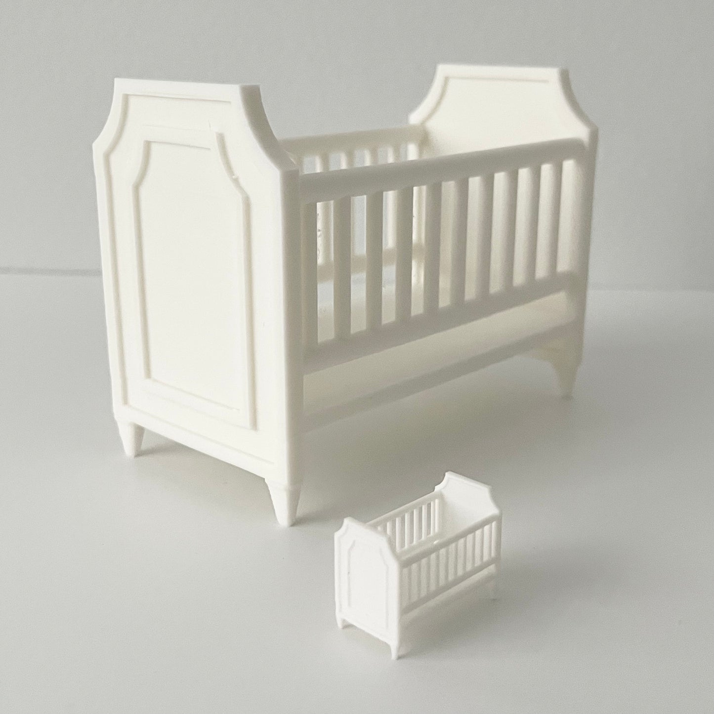 A white 1:12 Scale crib next to a miniature version in 1:48 Scale