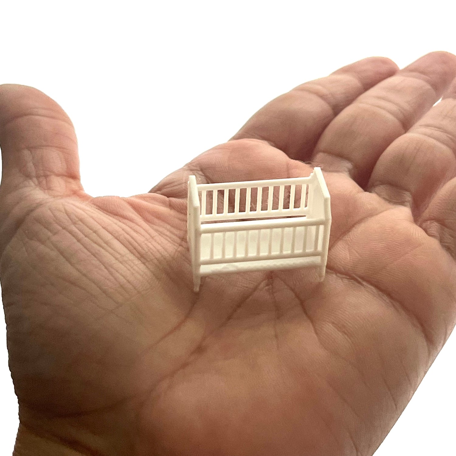 A miniature crib in 1:48 scale on a hand