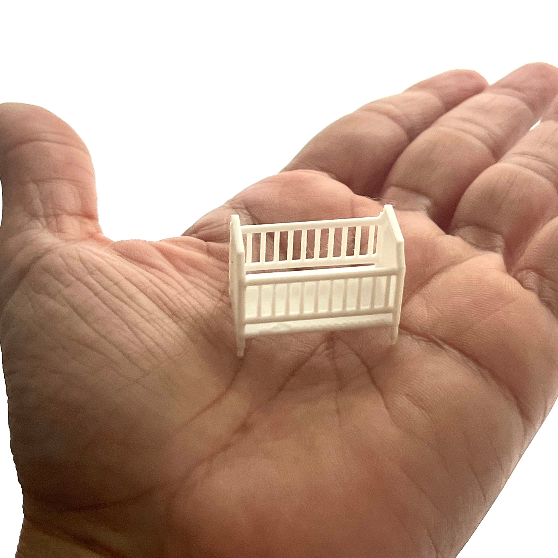 A miniature crib in 1:48 scale on a hand